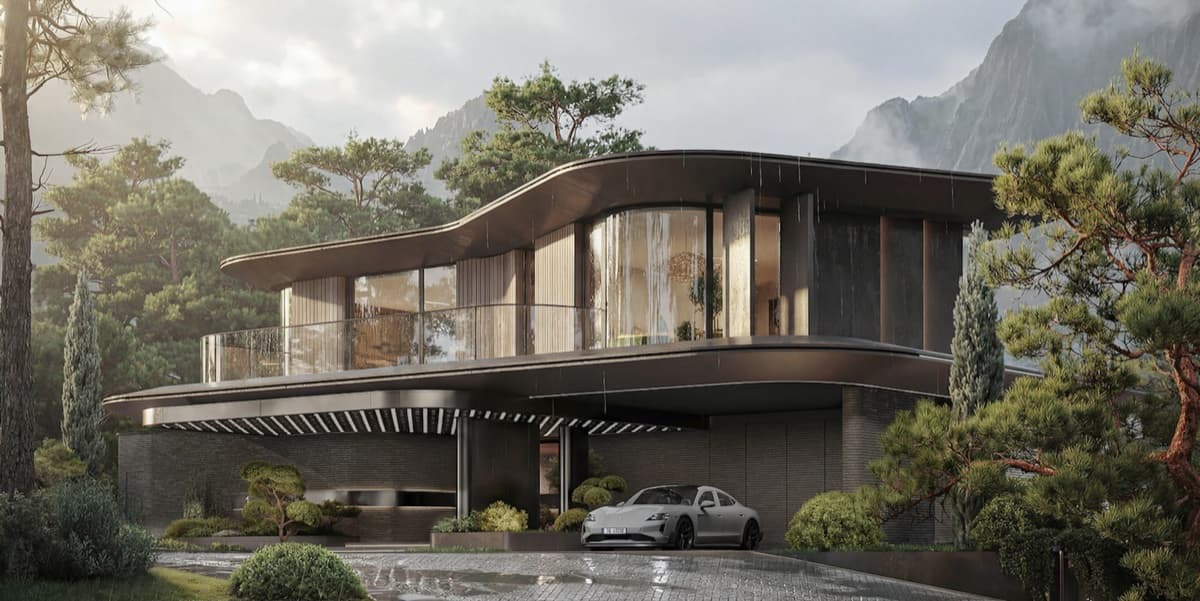 A modern house with a curved roof against a wooded mountainside