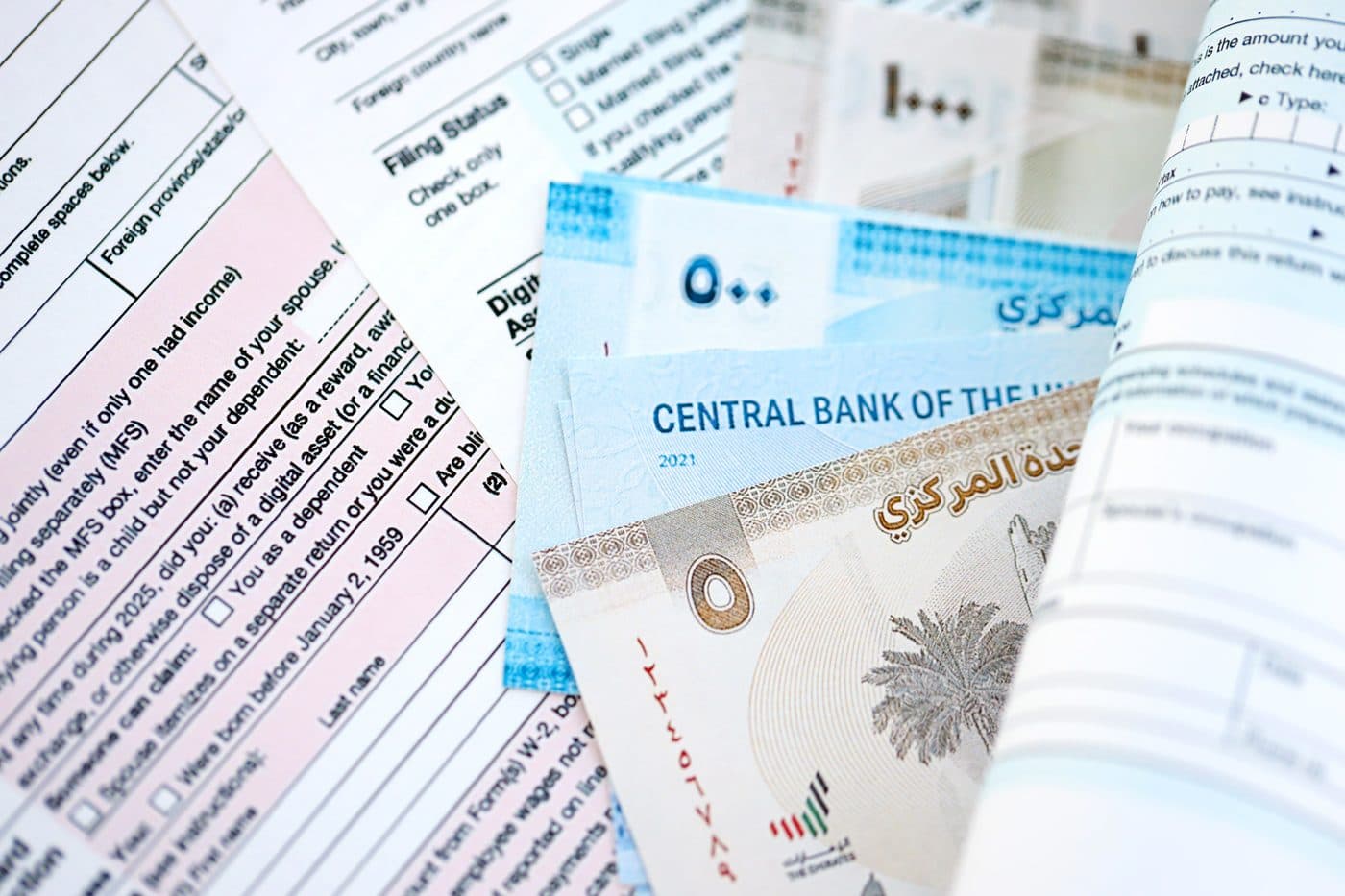 UAE dirham banknotes fanned across printed tax return forms