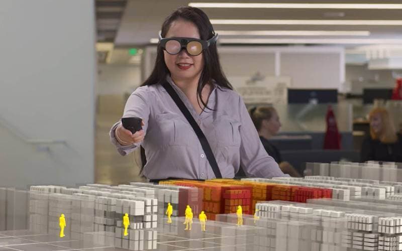 A person in augmented-reality glasses reviewing a scale model of a site.